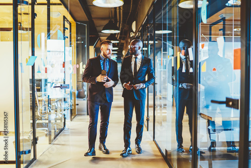 Calm adult multiracial businessmen talking in light office corridor