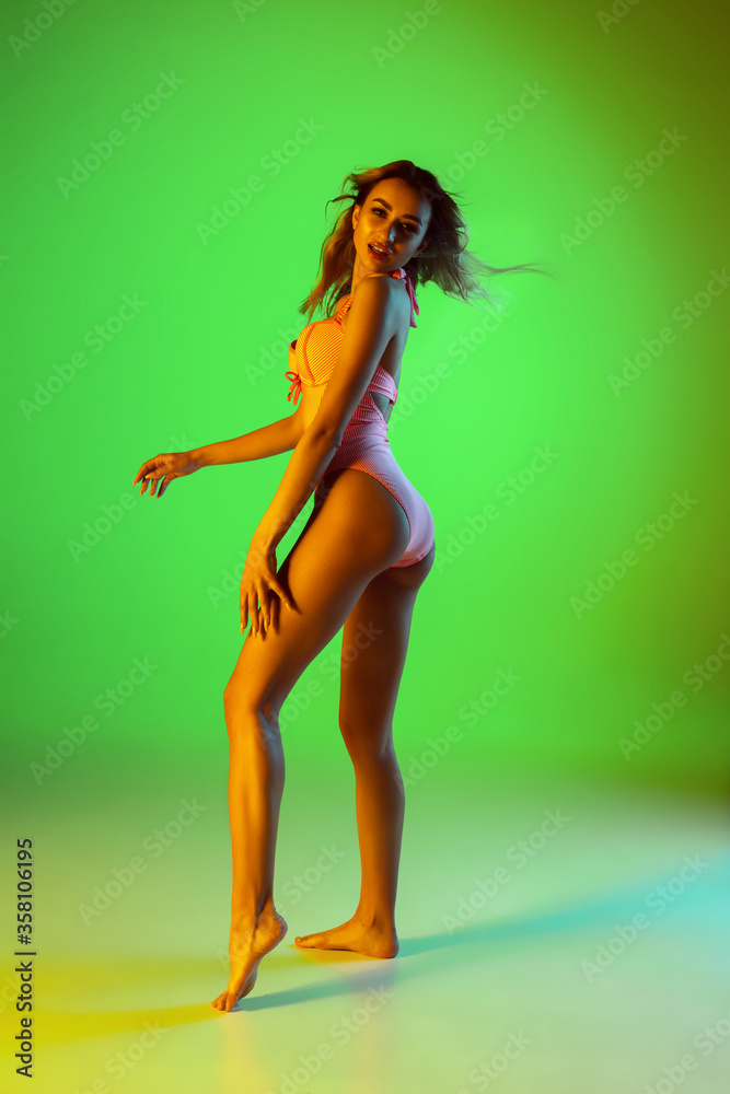 Beach. Beautiful young girl' portrait isolated on gradient studio background in neon light. Woman in fashionable bodysuit. Facial expression, summer, weekend, beauty, resort concept. Vacations. Beach. Beautiful young girl' portrait isolated on gradient studio background in neon light. Woman in fashionable bodysuit. Facial expression, summer, weekend, beauty, resort concept. Vacations.
