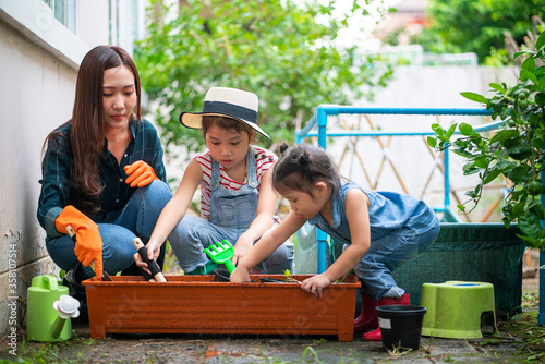 Asian beautiful woman with her daughter gardening her home vegetable garden at home during coronavirus outbreak situation. staycation, new normal concept photo