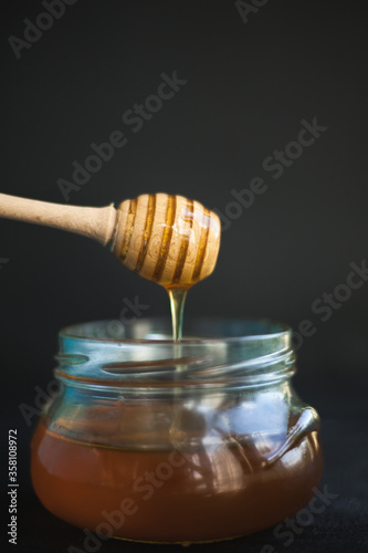 Honey and honey spoon on a light background. Sweet honey in the jar, place for text. 