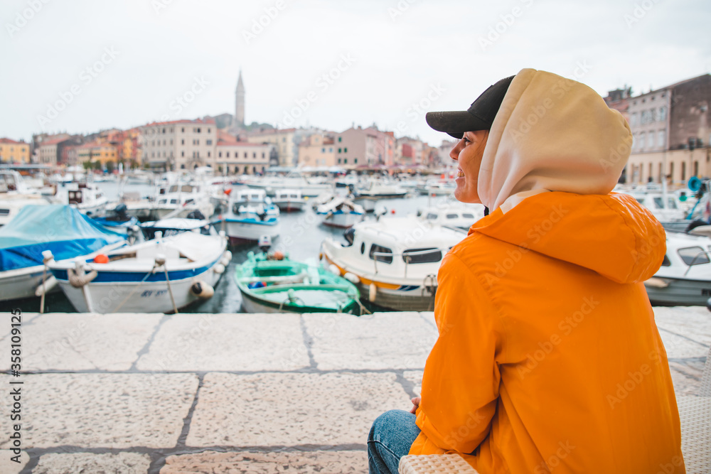 woman in yellow raincoat at rainy weather looking on rovinj city