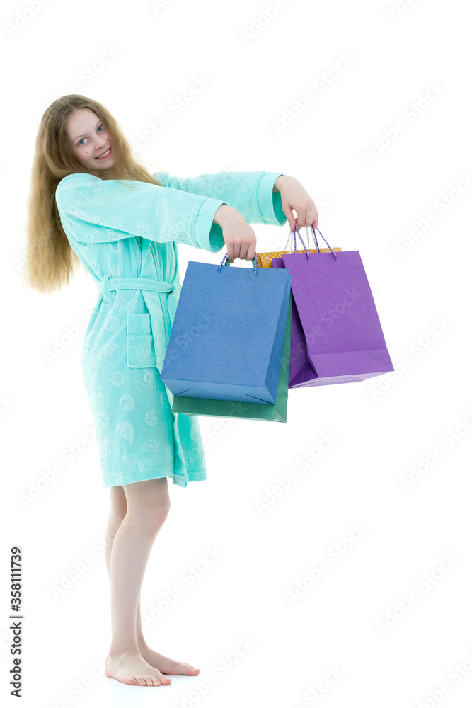 Cheerful girl in a short robe waving multicolored paper bags.