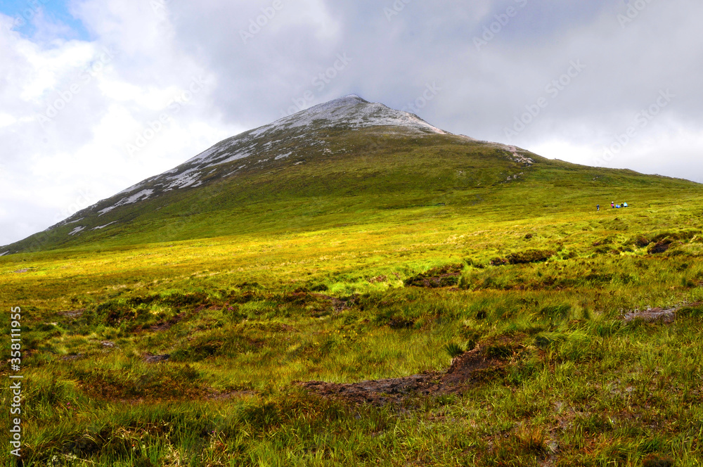 Fototapeta premium Vue sur le Mont Errigal perdu dans les nuages au nord-ouest de l'Irlande. Montagne solitaire à la verdure humide et sauvage.