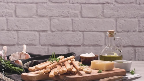 Fresh baked homemade grissini bread sticks in vintage metal grid box with olive oil and rosemary herbs over kitchen counter top. photo