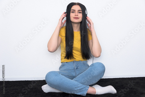 Joy and music. Young teenager enoy and listening the music in his room. White backgroung and yellow T-shirt. photo