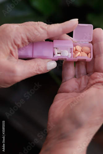 manos de mujer mayor sosteniendo un pastillero en su casa