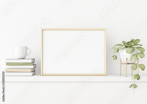 Poster mockup with horizontal gold metal frame on the table with green plant in pot, books, cup and trendy interior decoration on empty white wall background. A4, A3 size. 3D rendering, illustration.