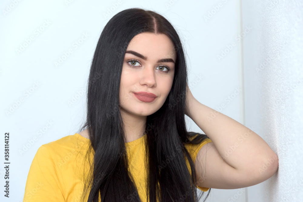 Beautiful young girl, surf on tablet and smiling. White background, yellow T-shirt and white background Beautiful young girl, surf on tablet and smiling. White background, yellow T-shirt and white background