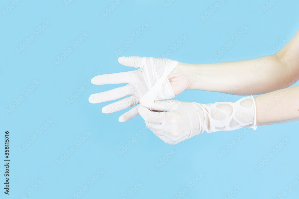 White latex medical gloves on a woman's hand,Taking off gloves isolated on blue background