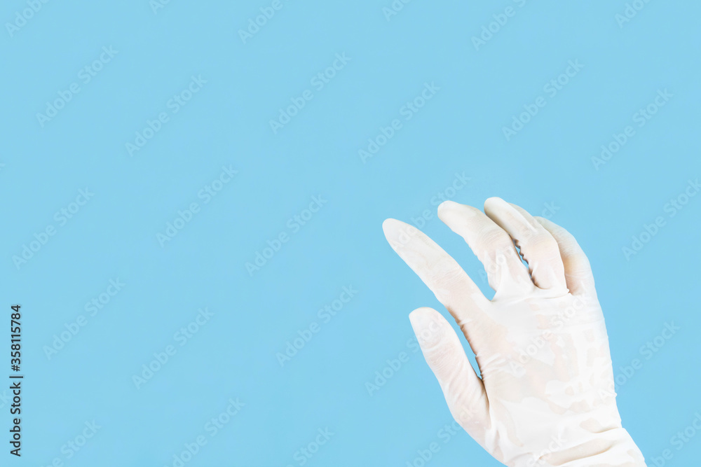 White latex medical gloves on a woman's hand outstretched isolated on blue background