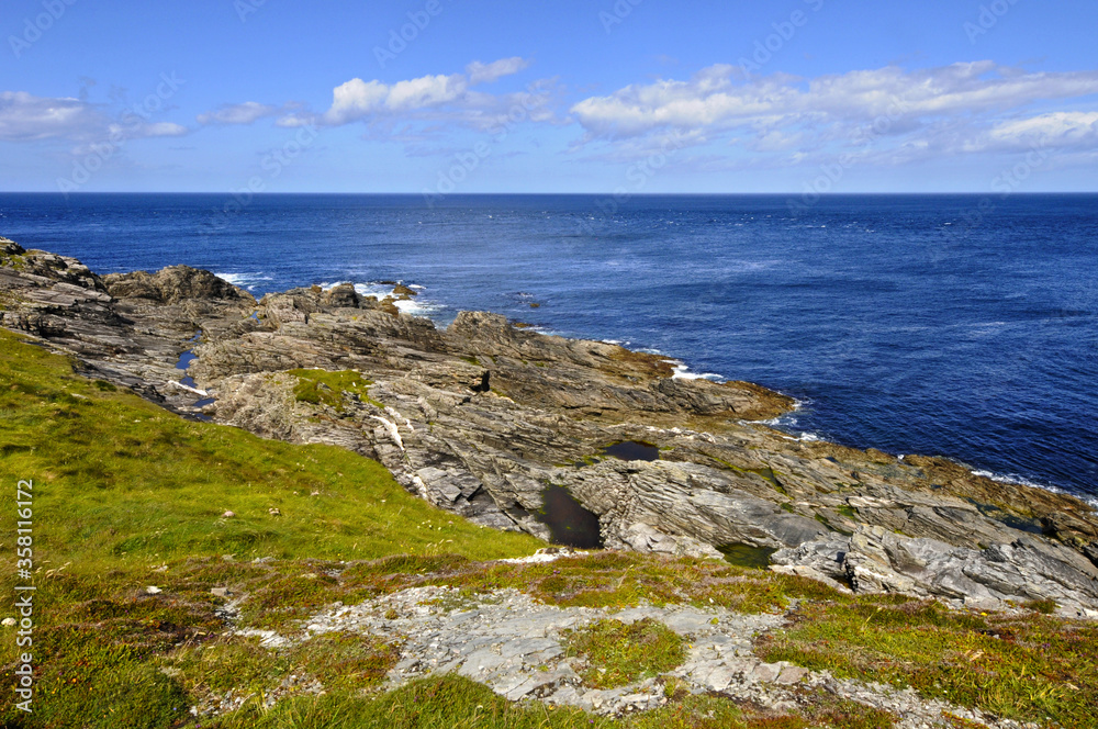 Vue panoramique sur l'horizon, les rochers et la mer bleue indigo depuis la côte verdoyante du nord de l'Irlande.