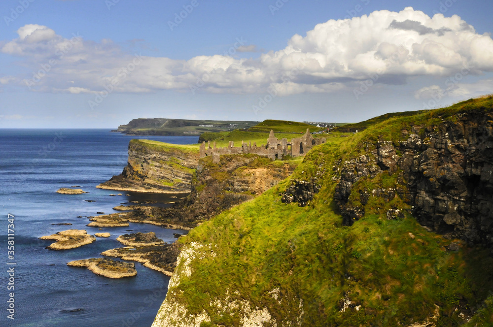 Vue panoramique sur les falaises verdoyantes et les ruines du château de Dunluce sur la côte nord irlandaise.