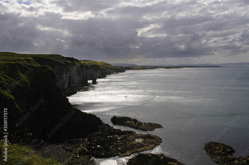 Vue sur les falaises vertes et les rochers du bord de mer, au soleil couchant en Irlande du nord.