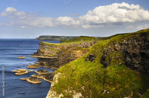 Vue panoramique sur les falaises verdoyantes et les ruines du château de Dunluce sur la côte nord irlandaise.
