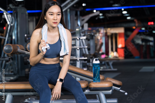 Asian women are sitting on the exercise and are holding towels with water bottles placed on their sides.