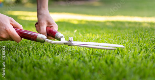 Symbol for perfection. A worker is using a hedge trimmer to cut the grass. photo
