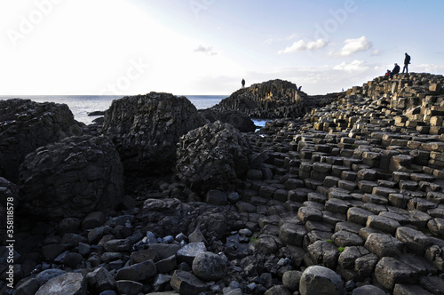 Vue sur les colonnes basaltiques hexagonales, la mer bleue et les gens marchant sur la chaussée des géants, cette zone géologique volcanique du nord de l'irlande.