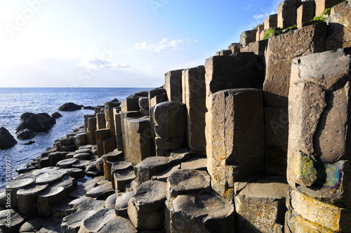 Vue sur les colonnes basaltiques hexagonales  la mer bleue et les gens marchant sur la chauss  e des g  ants  cette zone g  ologique volcanique du nord de l irlande.