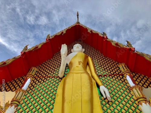 A large Buddha statue stands behind the church of Plong Agas Temple photo