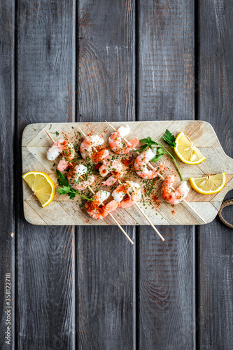 Shrimp skewers - seafood snack - on cutting bioard on wooden table top view copy space photo