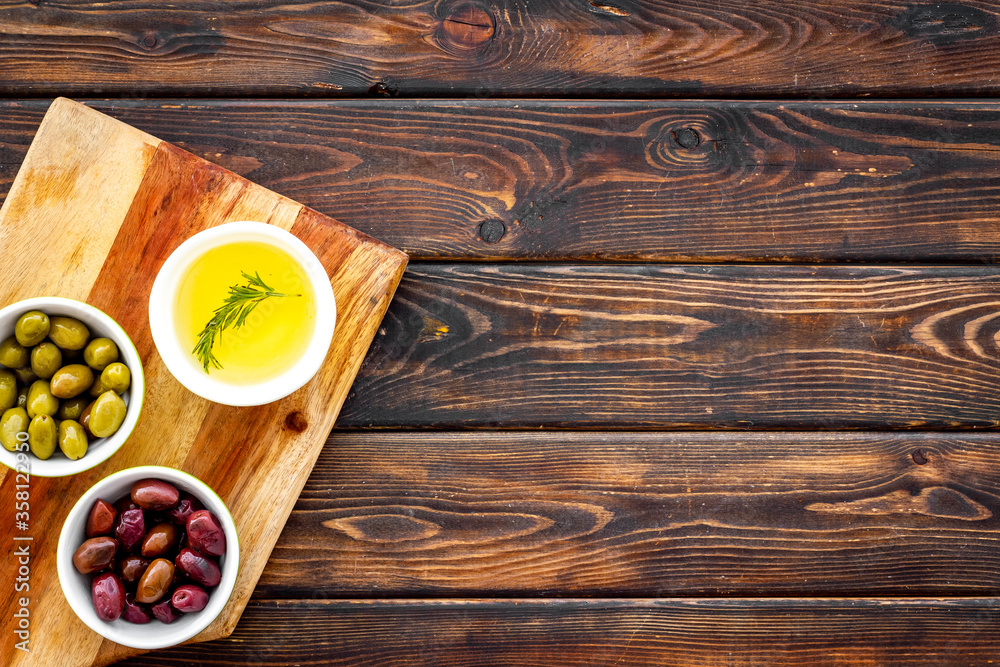 Green and black olives, olive oil in bowls on cutting board top-down copy space