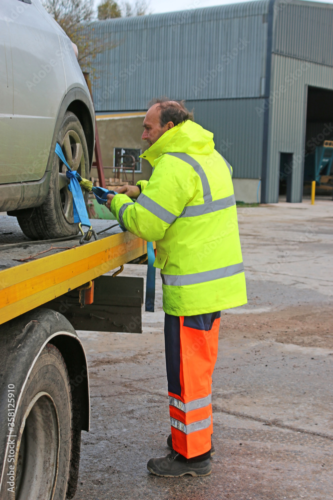 man loading car on a recovery truck man loading car on a recovery truck