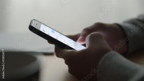 Side view. Hand of girl using smartphone at home, typing message Close-up 