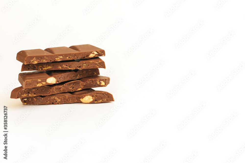 Chocolate slices are stacked on a white background.Dark chocolate with nuts. Chocolate slices are stacked on a white background.Dark chocolate with nuts.