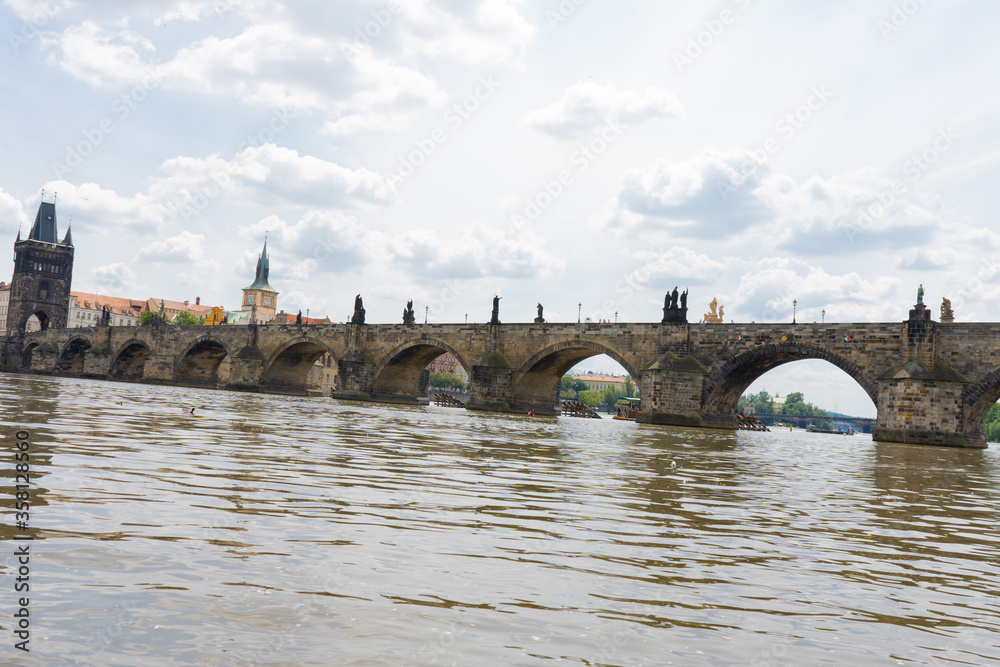 Charles Bridge in Prague in the center of Prague and the flowing Vltava River in summer and there are clouds in the sky