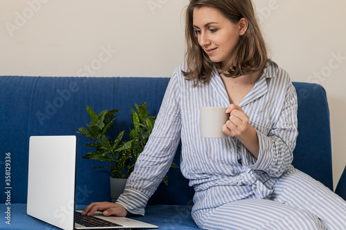 Work from home. Woman drinking coffee and using digital tablet in the morning. Hands on laptop