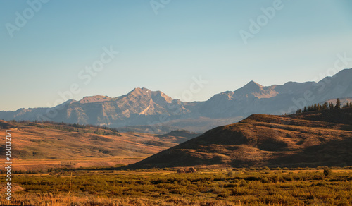 Wyoming landscape with foreground willow bottom and background sage covered hills and mountains.