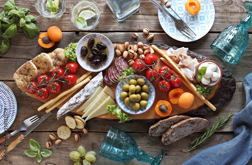 Mediterranean appetizers platter. Diner table with antipasto selection: cured meat and salami, gazpacho soup, jamon, olives, cheese, hummus and vegetables.   Overhead view.
