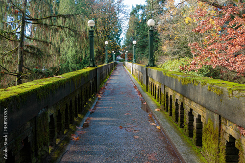 Receeding bridge pathway with moss covered side walls and decorative lights in autumn.