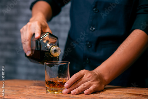 Barman pouring whiskey glass celebrate whiskey on a friendly party in  restaurant