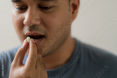 Close up handsome man taking pill. Medicine, health care concept.