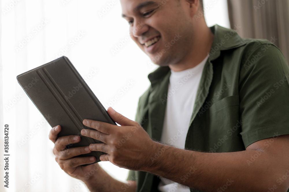 Handsome man checking social media with tablet computer at the the bedroom, living room. Communication and technology concept Handsome man checking social media with tablet computer at the the bedroom, living room. Communication and technology concept