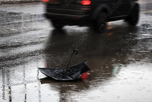 Broken black umbrella against the background of a passing car