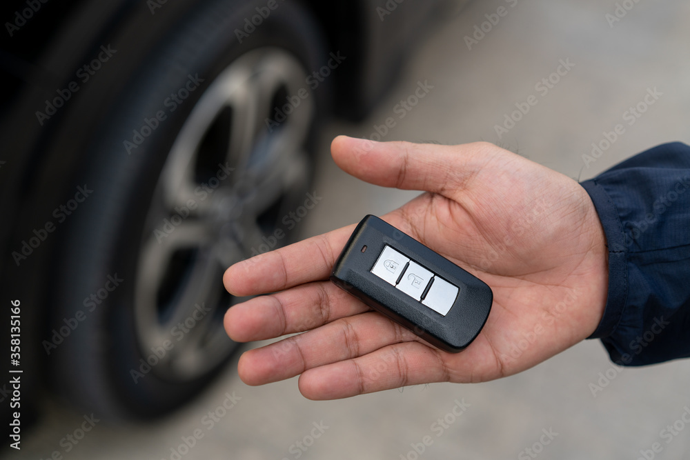 Close up car keys and remote control car alarm systems hold in hand Close up car keys and remote control car alarm systems hold in hand