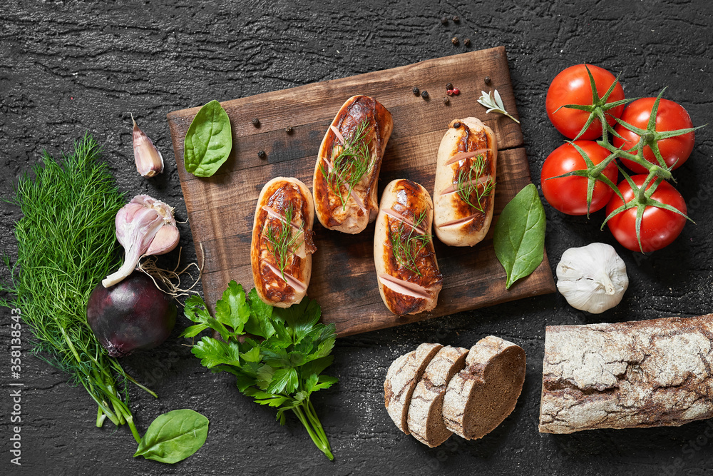grilled sausages with tomatoes and herbs on the board on a wooden table