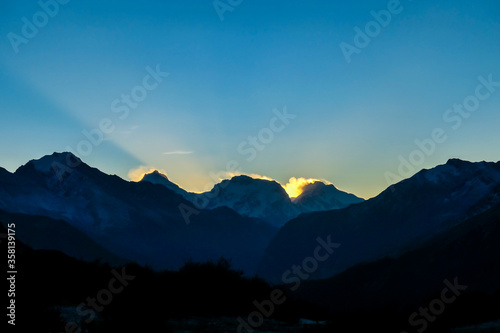 A soft and early sunset in the nearby of Thorung La Pass, Annapurna Circuit Trek, Nepal. Harsh and barren landscape around. Clear and blue sky. High Himalayan ranges in the back. Snow capped mountains
