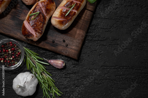 grilled sausages with herbs on the board on a wooden table with copy space