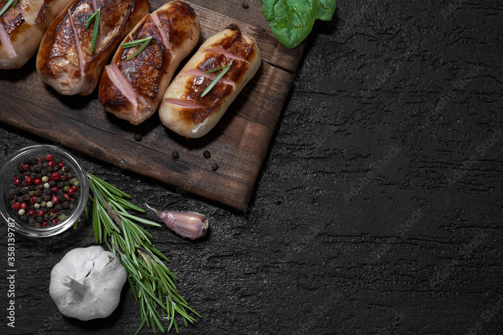 grilled sausages with herbs on the board on a wooden table with copy space