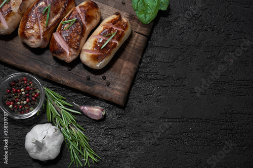 Obraz na płótnie grilled sausages with herbs on the board on a wooden table with copy space w salonie