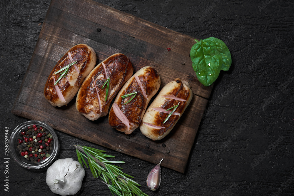 grilled sausages with herbs on the board on a wooden table with copy space