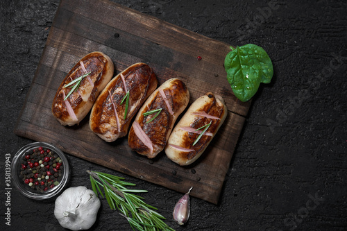 Obraz na płótnie grilled sausages with herbs on the board on a wooden table with copy space w salonie