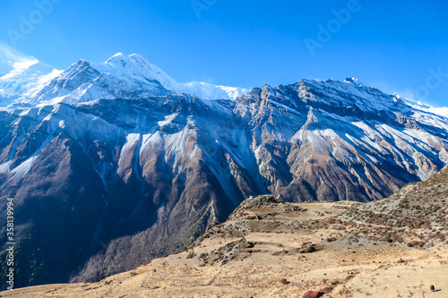 An abandoned ruins of a fortress in Manang Valley Annapurna Circuit Trek, Nepal. There are multiple mountain chains. Sunbeams breaching through the peaks. The fortress has the view on Annapurna chain © Chris