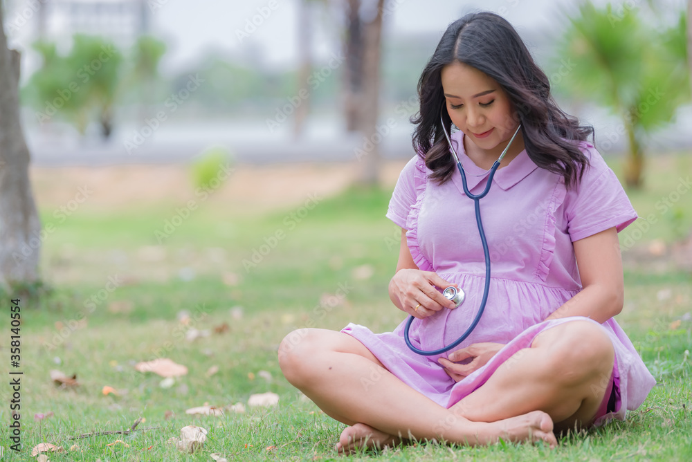 Portrait of asian Beautiful pregnant woman at the park,Thailand people,Happy woman concept,Her use hand touch her belly,Mother day concept Portrait of asian Beautiful pregnant woman at the park,Thailand people,Happy woman concept,Her use hand touch her belly,Mother day concept