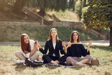 Students in a park. Girls lying on a grass. Friends with a laptop.
