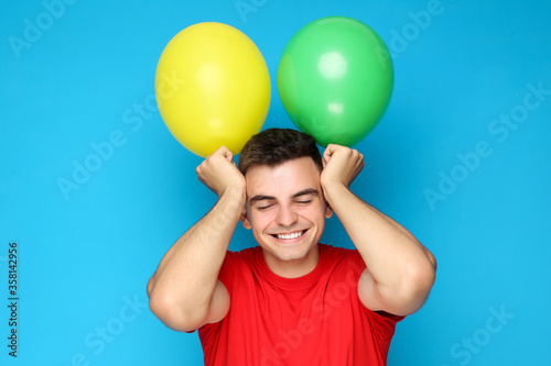 Yuong man with balloons on blue background © 5second