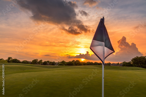 Sunset sky over the fairway of a golf course in Texas with a golf flag in the foreground